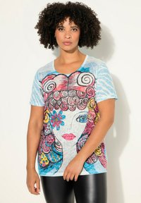 Camiseta colorida con un diseño gráfico de cara, fondo azul y mangas cortas. Tejido suave con una textura ligera.
