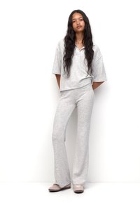 Ensemble assorti gris clair avec un haut ample à manches courtes et un pantalon évasé, fabriqué dans un tissu doux et texturé. Présente un col sur le haut.