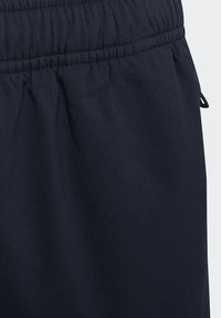 Navy athletic shorts made of lightweight fabric with an elastic waistband and drawstring. Features a smooth texture and subtle pattern.