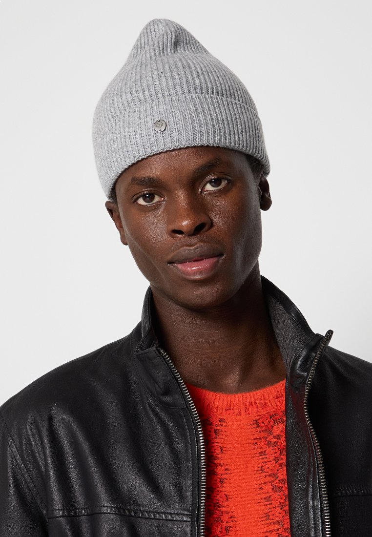 Szara dziana czapka z pionowym prążkowaniem, z charakterystycznym stożkowatym wierzchołkiem i małym metalowym akcentem. Noszona z czarną skórzaną kurtką i czerwoną bluzą.