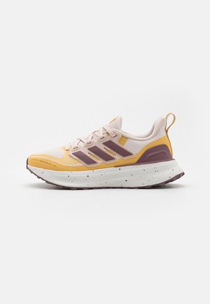 Yellow and pink athletic shoe with a textured upper, mesh panels, purple accents, and a speckled white midsole. Features a pull tab at the heel.