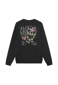 Melna jakas ar ziedu apdruku aizmugurē, kurā ir teksts "Jaunā Jorkas pilsētas ziedu tirgus 2024" un botāniskās ilustrācijas rozā un zaļā krāsā.