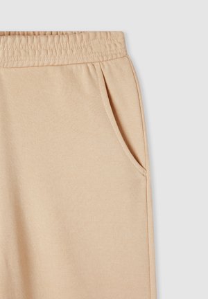 Beżowe dresy bawełniane z elastyczną talią, bocznymi kieszeniami i miękką fakturą. Gładki design bez widocznych wzorów.