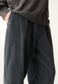 Donkergrijze corduroybroek met een ribbeltextuur en een relaxte pasvorm, voorzien van zijzakken en een elastische tailleband.
