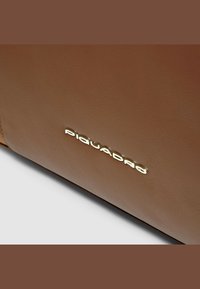 Braune Lederbrieftasche mit feiner Struktur und goldenem, geprägtem Logo. Das Design ist elegant mit klaren Linien und minimaler Hardware.