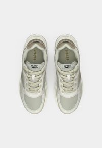 Jasnoszare siateczkowe sneakersy z beżowymi akcentami, okrągły nosek, sznurowanie i oznaczenie marki na języku. Teksturowana powierzchnia.