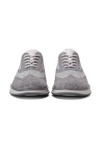 Las zapatillas de punto grises cuentan con un upper texturizado, cordones planos y una suela suave y acolchada con acentos claros. Diseño de punta redondeada con un perfil bajo.