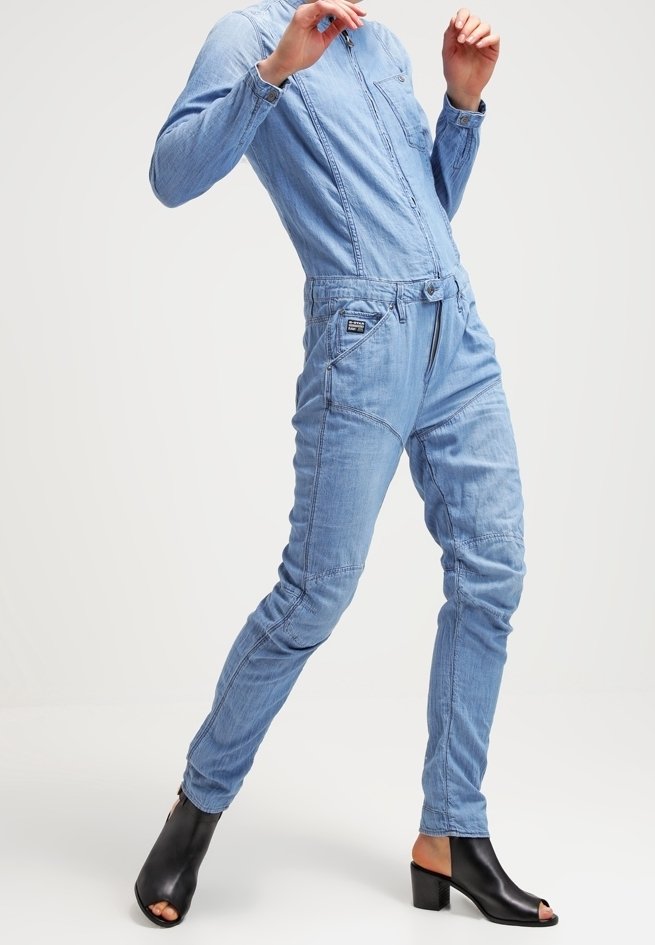 Ljusblå denimoverall med framsidans dragkedjestängning, bröstficka, elastisk midja och avsmalnande ben. Matchas med svarta klackskor med öppen tå.