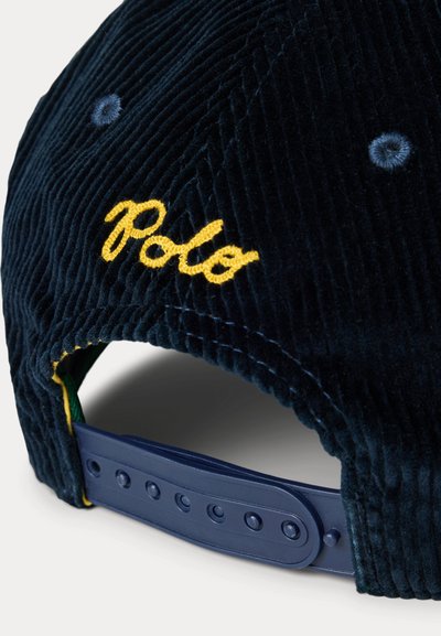 Casquette en velours côtelé marine avec logo "Polo" jaune brodé, sangle réglable en plastique avec plusieurs trous, surface texturée et détails cousus.