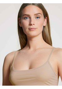 Nude camisole top met dunne bandjes, gemaakt van een zachte, elastische stof en een getailleerd ontwerp dat zich aan het lichaam aanpast.