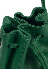 Sac à main en cuir vert avec une finition texturée et des bords supérieurs ondulés. Dispose d'une fermeture par cordon et de détails de surpiqûres contrastantes.