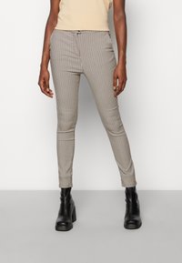 Bukser med et brun og cremefarvet ternet mønster, slim fit, med en mid-rise talje. Parret med sorte plateau ankelstøvler.