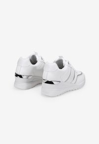 Zapatillas blancas hechas de material sintético. Cuentan con un acento metálico plateado en el talón, detalles texturizados y una suela gruesa para mayor soporte.