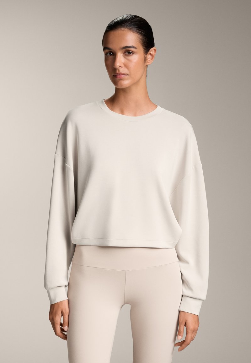 Világos bézs pulóver, laza fazonnal, kerek nyakkal és hosszú ujjakkal, hozzá illő bézs leggingsszel. Puha anyag, minimalista dizájn.