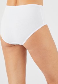 Witte katoenen slip met hoge taille, een zachte textuur en een elastische tailleband. Kenmerken zijn een délicate gestikte zoom en een minimalistisch ontwerp.