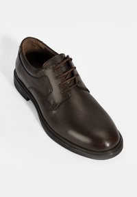 Braune Lederschuhe mit glatter Textur, runder Zehenform und fünf Ösen zum Schnüren. Mit einer schwarzen Gummisohle und dezentem Nähen.