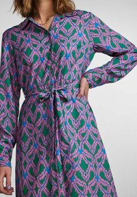Färgglad skjortklänning med ett mönstrat tyg i grönt, blått och rosa, långärmad och med midjeband för justerbar passform.