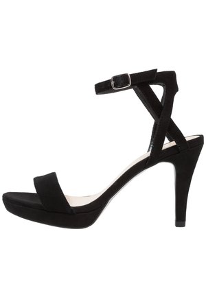 Sort højhælet sandal med ankelrem, åben tå og spænde, vist mod en ensfarvet hvid baggrund.