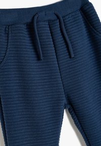 Marineblå ribbede sweatpants har en elastisk talje med snoretræk, sidelommer og en blød tekstur for komfort.