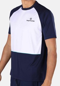 Marineblauwe en witte sportshirt met korte mouwen, voorzien van een contrasterende lijn en logo op de borst. Soepele textuur en een ontspannen pasvorm.