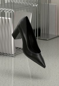 Pump nera in pelle con tacco alto, punta affusolata e tacco a blocco, caratterizzata da una texture liscia e un design minimalista.