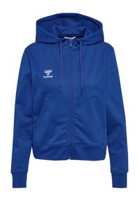 Sudadera azul con cremallera, hecha de una tela de textura suave. Presenta una capucha con cordón, puños acanalados y bolsillos frontales. Logo de Hummel en el pecho.