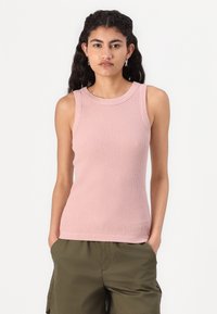 Helles Rosa, geripptes Top mit rundem Halsausschnitt und breiten Schulterträgern, kombiniert mit olivgrünen Cargo-Hosen. Strukturierte Stoffdetails.