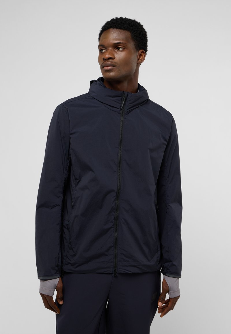 Marineblauer leichter Jacke mit Kapuze, durchgehendem Reißverschluss, seitlichen Taschen und elastischen Bündchen. Glatte Textur und minimalistisches Design.