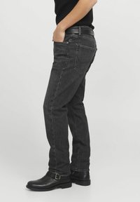 Mörkgrå denimjeans med rak passform, som har fem fickor, synliga sömmar och sliten textur, kombinerade med svarta läderankelboots.