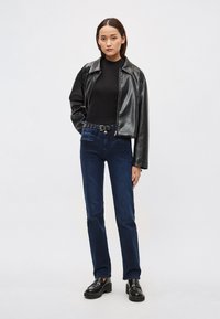 Fekete bőrkabát galléros kialakítással, testhezálló fekete garbó, sötétkék farmernadrág és masszív fekete platform cipők.