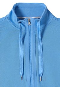 Veste zippée bleu clair avec un col montant et des cordons tressés se terminant par des embouts en métal argenté.