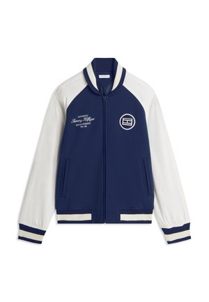 Marineblauwe en witte jas met rits, witte mouwen, gestreepte geribde boorden en kraag, voorzakken, en geborduurde tekst en logo op de borst.