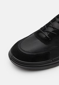 Černá bota s kombinací kůže a semiše, kulatou špičkou, plochým zavazováním na tkaničky a texturovanými detaily.