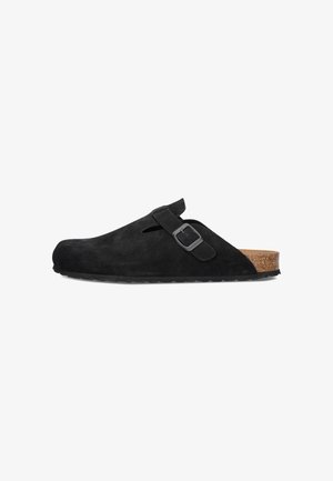 Schwarzer Wildleder-Schlupf-Clog mit verstellbarem Riemen und Schnalle, Kork-Fußbett und schwarzer Gummisohle, seitlich auf weißem Hintergrund dargestellt.