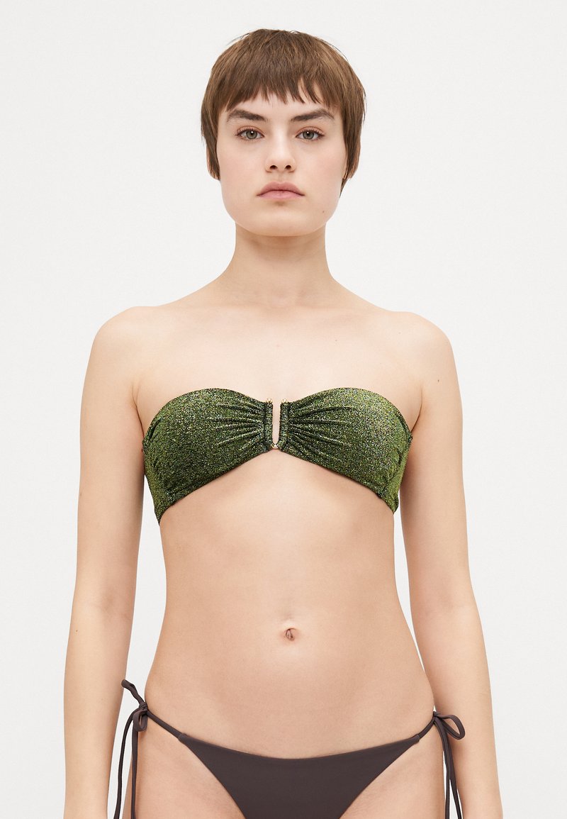Žalias blizgus bandeau tipo bikini viršus su raukiniais ir metaliniu akcentu centre, derinamas su viengubo rudo kaspinėlio šonu.