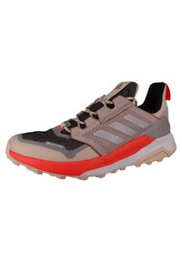 Trail running shoe with a beige, black, and orange design. Features a breathable mesh upper, textured sole, and GORE-TEX branding.