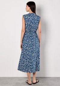 Abito senza maniche, lungo fino alla caviglia, in tessuto blu con un motivo a stampa leopardo bianco. Vita elasticizzata con dettaglio arricciato sul retro.
