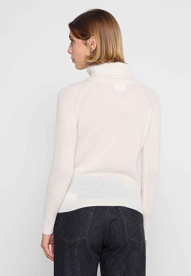 Helles Cremefarbenes Rollkragensweatshirt mit gerippten Bündchen und Saum, aus weichem, strukturiertem Strickmaterial. Mit rückseitiger Nahtdetails.