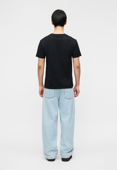 T-shirt noir à manches courtes associé à un jean denim bleu clair ample. Le tissu semble doux avec un col rond classique.