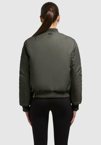 Oliven grøn bomberjakke med ribbede manchetter og kant, der har et glat, skinnende stof og et bagpaneldesign med minimalistiske detaljer.