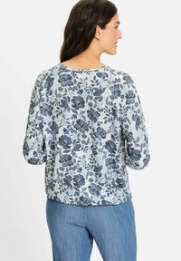 Bluse mit Blumenmuster in Blau und Weiß, ausgestattet mit 3/4-Ärmeln und einem runden Ausschnitt. Weicher Stoff mit lässigem Schnitt und filigranen Details.
