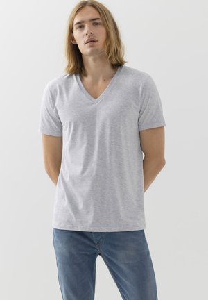 Grijze V-hals T-shirt gemaakt van zachte katoen, korte mouwen en een relaxte pasvorm. Gdragen met blauwe jeans, met een eenvoudig ontwerp en een gladde textuur.