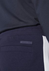 Marinblå joggers med vit sidopanel, med en bakficka och en broderad Michael Kors-logotyp i matchande blått. Tillverkade i mjukt bomullsblandat material.