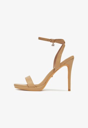 Beżowy sandał na wysokim obcasie z platformą, paskiem wokół kostki i klamrą. Charakteryzuje się gładką skórzaną fakturą oraz smukłym obcasem typu szpilka.