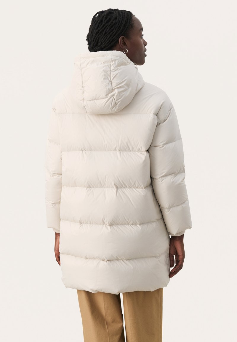 Biała kurtka puchowa z kapturem, o pikowanej konstrukcji, luźnym kroju i prążkowanych mankietach. Gładka tekstura, średniej długości.