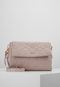 Quiltet lys rosa håndtaske lavet af syntetisk materiale; har et logo i guldfarve, klaplukning og aftagelig skulderrem.