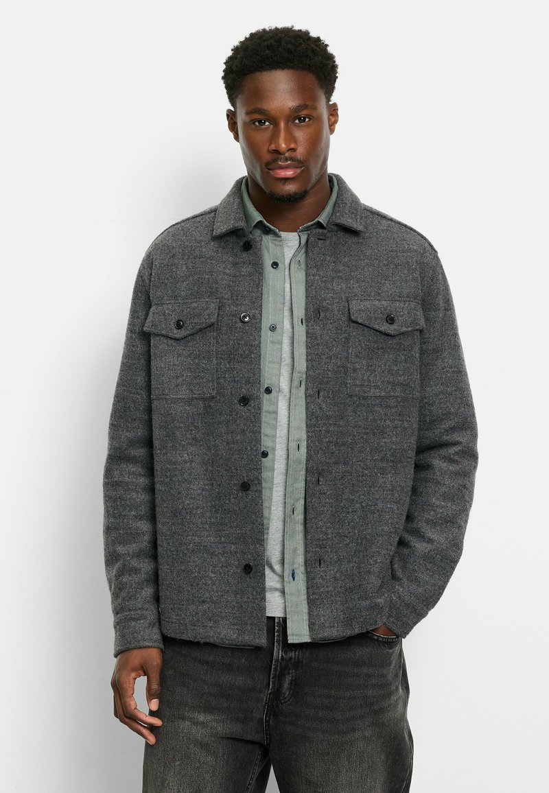 Gray wool jacket with a collar, two chest pockets, and black snap buttons, layered over a light green shirt. Textured fabric with a casual fit.