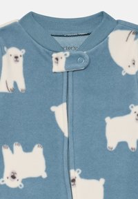 Sininen fleece-unisakki, jossa on valkoisten jääkarhujen kuvio. Siinä on nappikiinnitys ja pehmeä rakenne, joka sopii mukavuuteen.