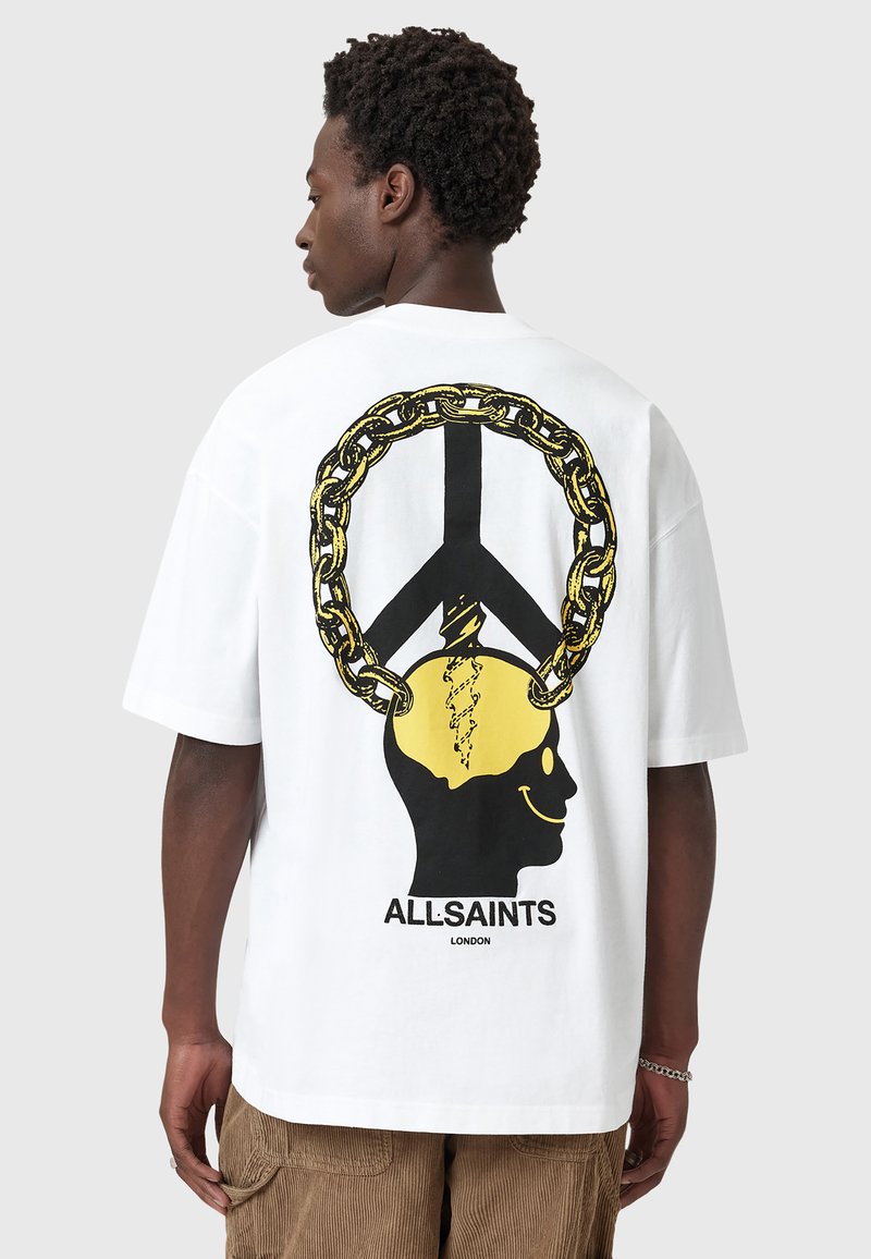 Hvid grafisk t-shirt med et sort og gult print af et skelet med et fredssymbol og kædedesign på ryggen. Fremstillet af bomuld.