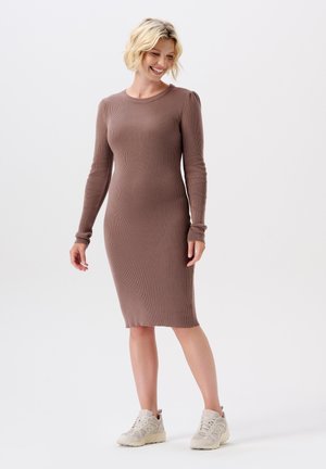 Ribbed braunes Kleid mit langen Ärmeln und einem mittellangen Saum, das eine figurschmeichelnde Silhouette hat. Kombiniert mit hellen Sneakers.